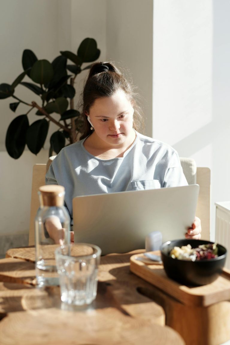 Woman in a Blue Top Using a Laptop 